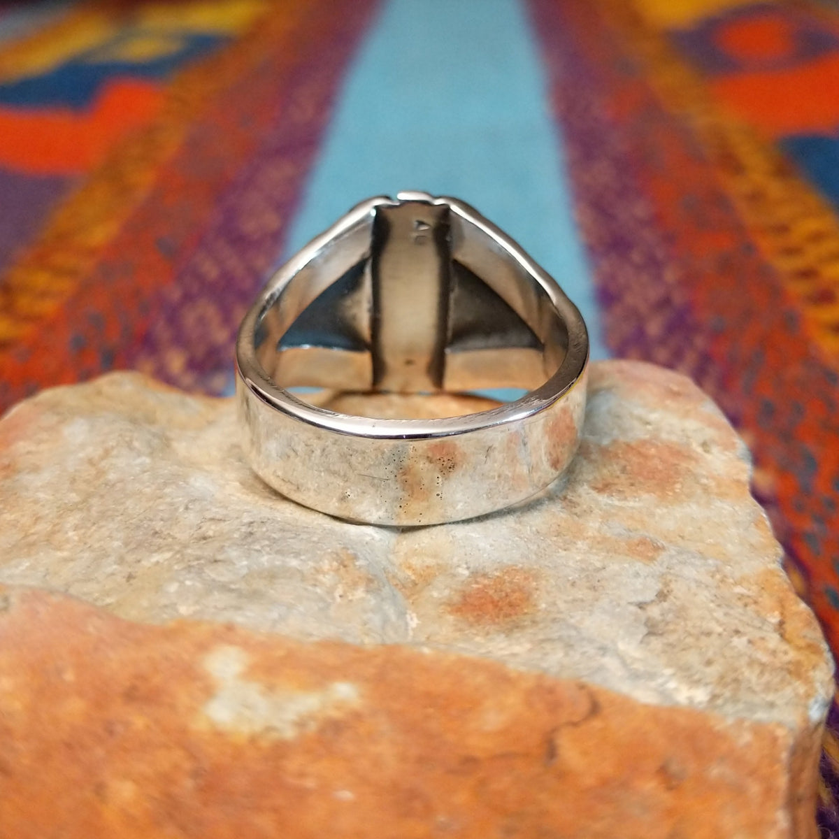 Tiered Turquoise Ring by Augustine Largo featuring an oval blue turquoise cabochon in a serrated bezel, surrounded by layered, symmetrical silverwork with radiating stamped details; underside view.