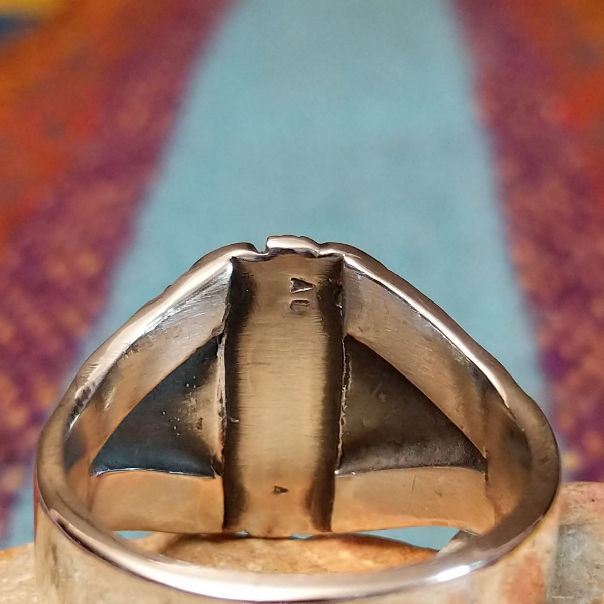 Tiered Turquoise Ring by Augustine Largo featuring an oval blue turquoise cabochon in a serrated bezel, surrounded by layered, symmetrical silverwork with radiating stamped details; artisan stamp.