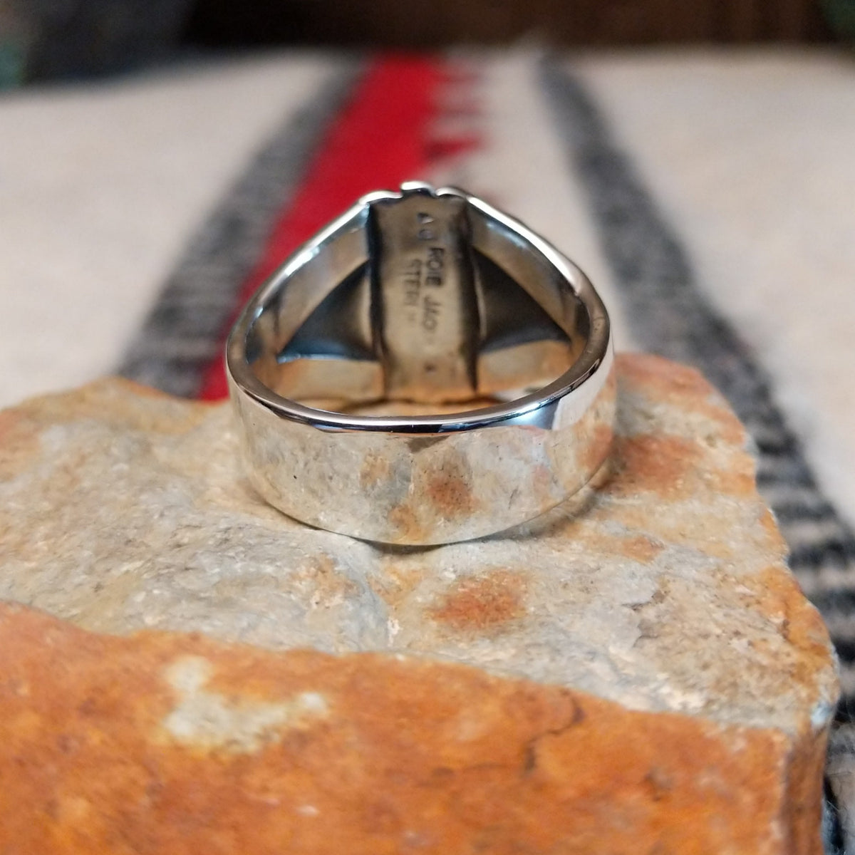 Turquoise ring by Roie Jaque featuring an oval bright blue turquoise stone in a serrated bezel, surrounded by layered, symmetrical silverwork with oxidized accents; underside view.