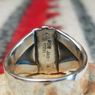 Turquoise ring by Roie Jaque featuring an oval bright blue turquoise stone in a serrated bezel, surrounded by layered, symmetrical silverwork with oxidized accents; artisan and Sterling Silver stamp.