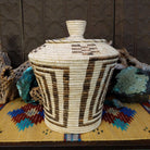 Award-winning Tohono O'odham handwoven lidded basket by Mary Thomas with geometric woven patterns in natural and dark fibers.
