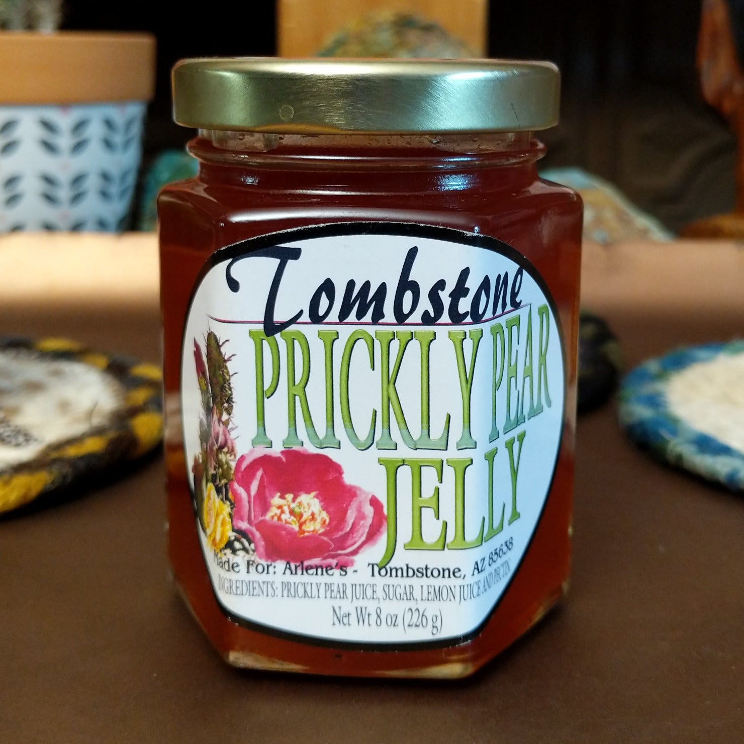 Jar of Tombstone Prickly Pear Jelly with a bright pink-purple color. Southwestern-style fruit jelly made from prickly pear cactus, ideal for spreading on toast, biscuits, or pairing with cheese.