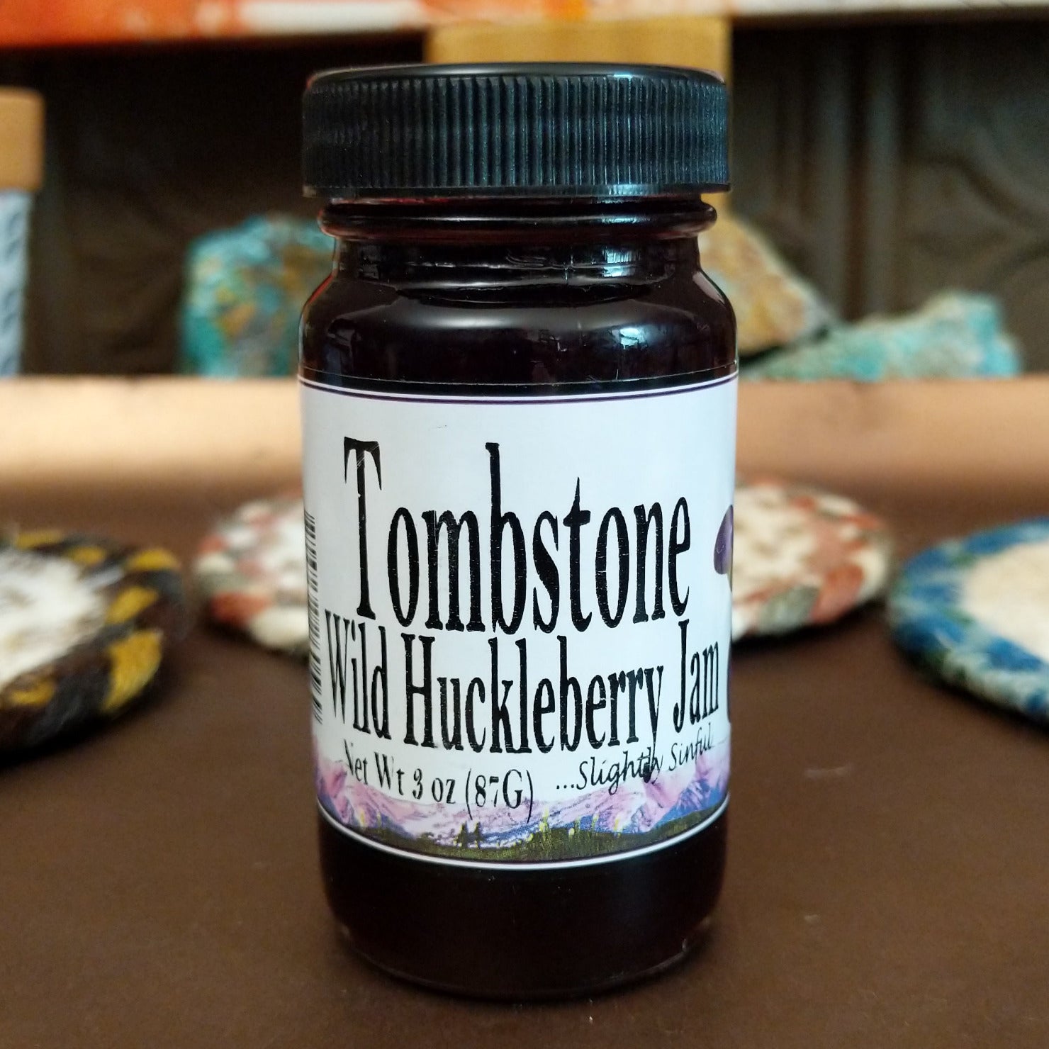 Tombstone Wild Huckleberry Jam 3 ounce bottle on a table.