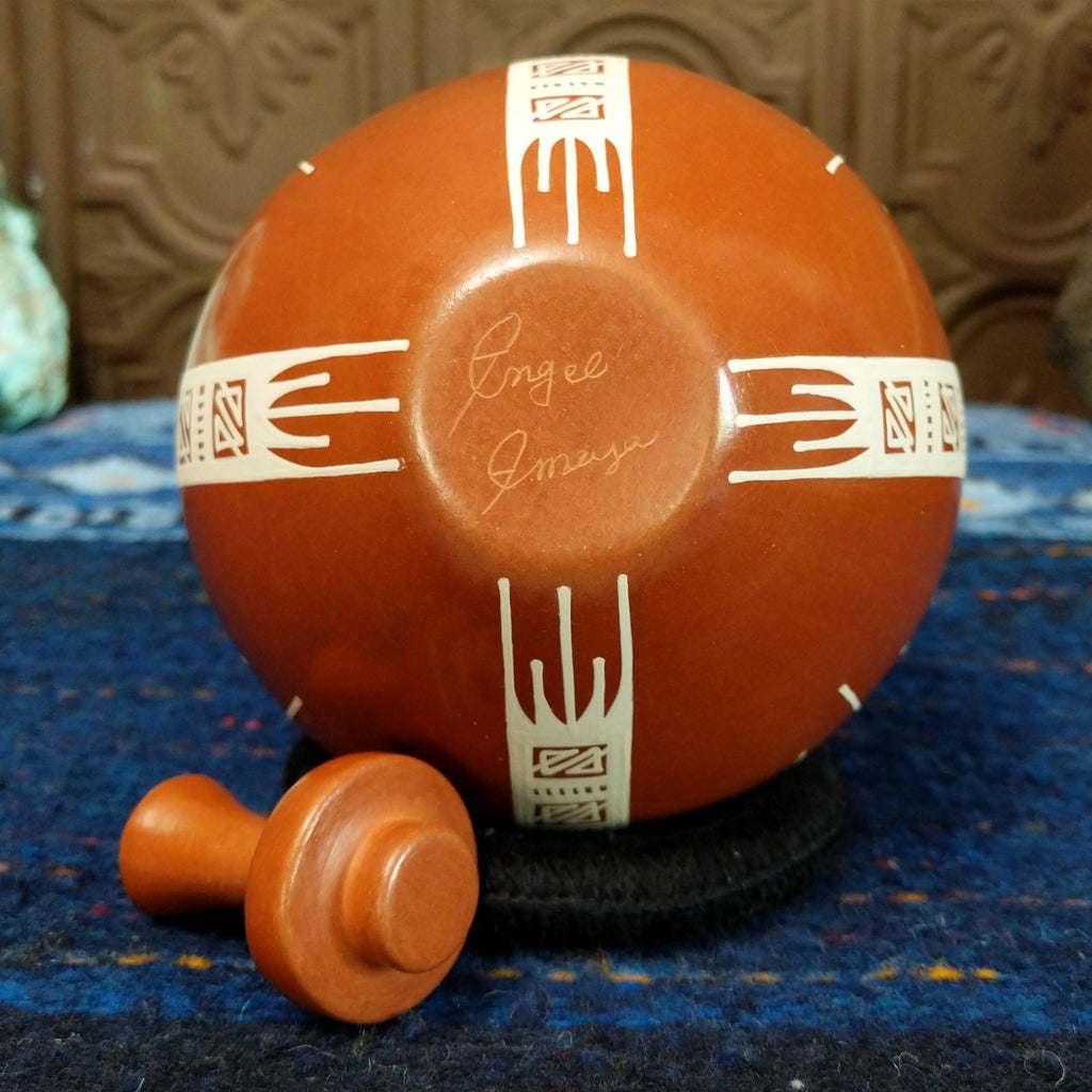 The artist's signature is etched at the base of the pot.