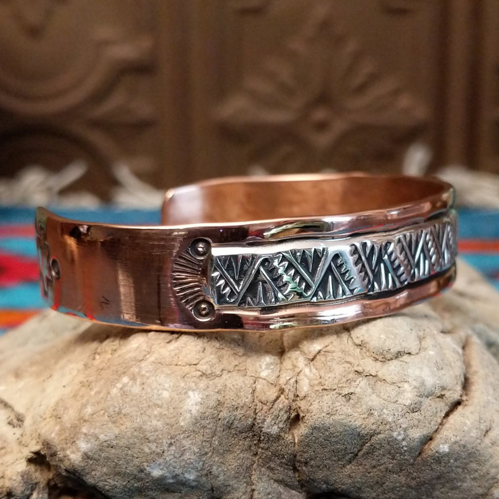 Copper and sterling silver cuff with intricate triangular stamping and polished finish.