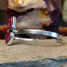 A sterling silver cuff displays two triangular purple spiny oyster shells and thin band.