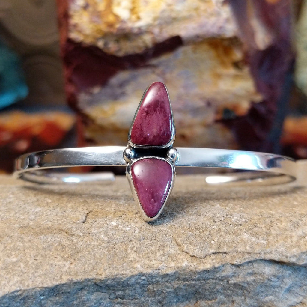 A sterling silver cuff displays two triangular purple spiny oyster shells.