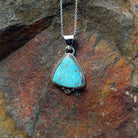 Triangular turquoise pendant by Burt Francisco featuring a bright blue turquoise stone framed with twisted sterling silver rope and decorative silver drops.