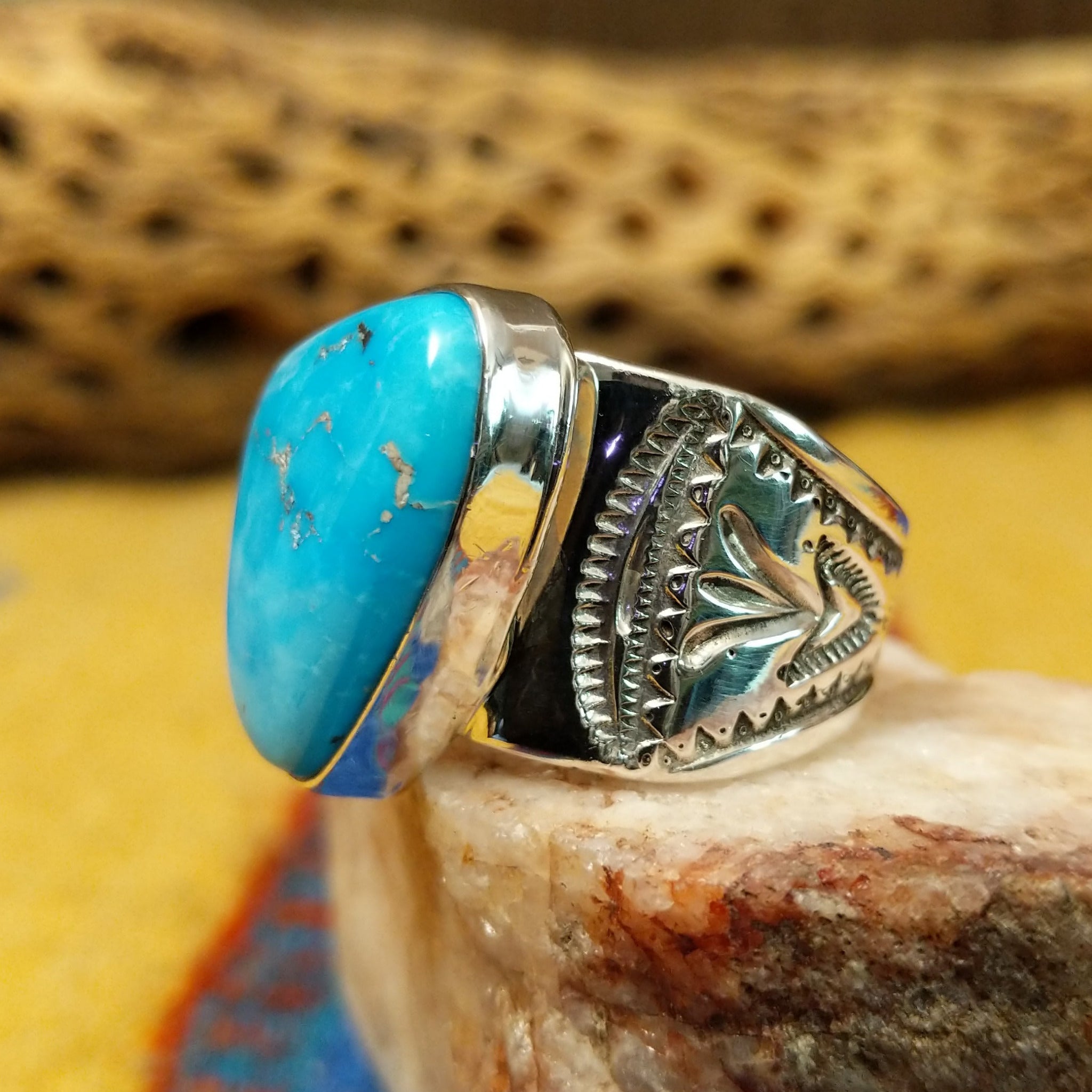 Triangular turquoise ring by E. Piaso, featuring a vibrant blue turquoise stone with natural matrix set in a handcrafted sterling silver band.  Side view.