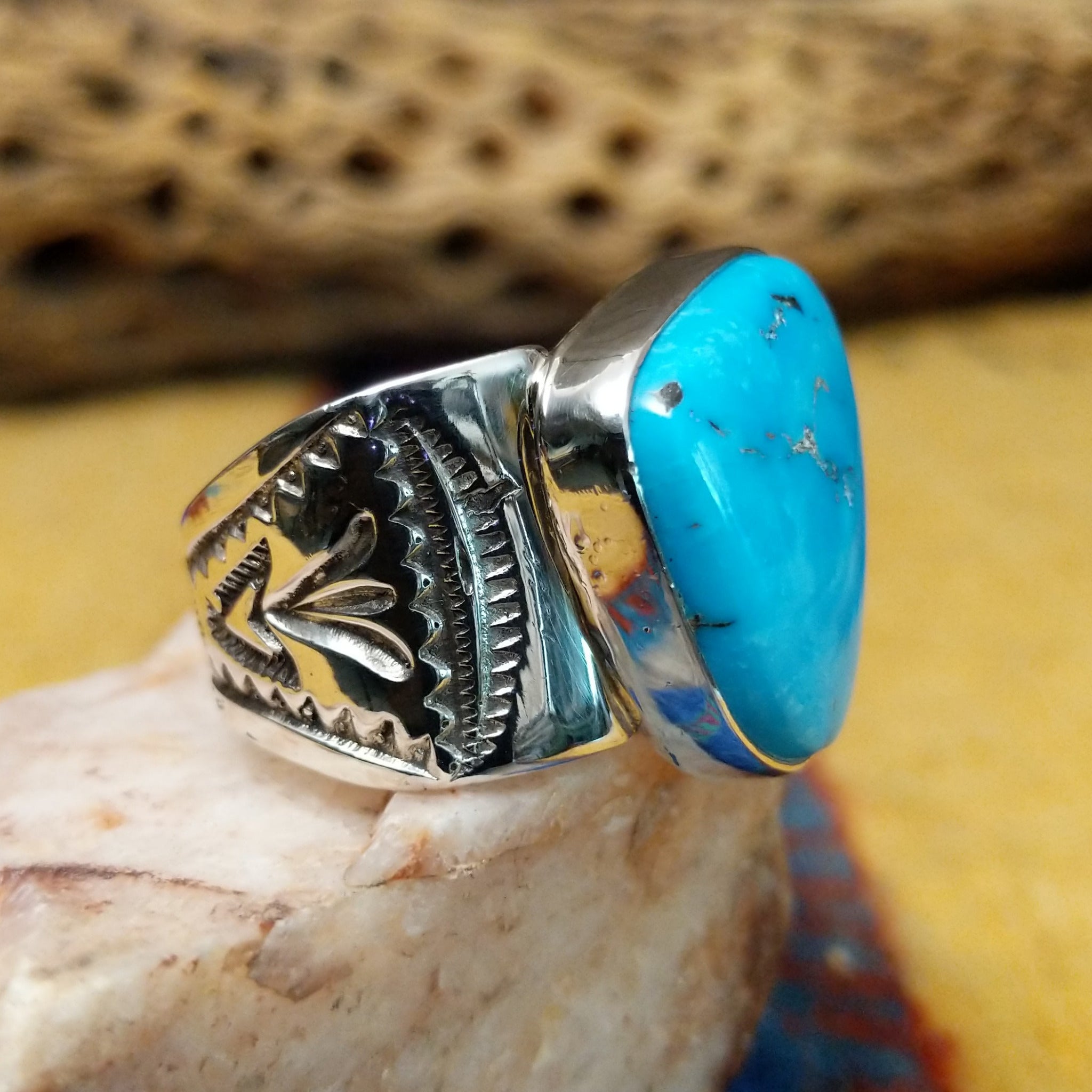 Triangular turquoise ring by E. Piaso, featuring a vibrant blue turquoise stone with natural matrix set in a handcrafted sterling silver band.  Side view.