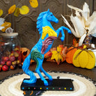 Pony in a rearing position painted blue with yellow, purple, and green horse heads on the body.