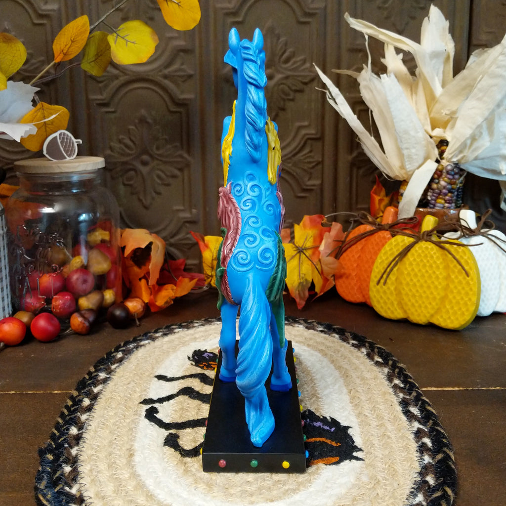 Pony in a rearing position painted blue with yellow, purple, and green horse heads on the body.