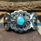 Turquoise cuff by Eugene Mitchell, featuring an oval blue turquoise stone set in a handcrafted sterling silver cuff with an intricate floral cutout design.