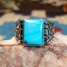 Sterling silver ring with turquoise set in the rectangular bezel and abstract stamped band.