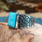 Sterling silver ring with turquoise set in the rectangular bezel and abstract stamped band.