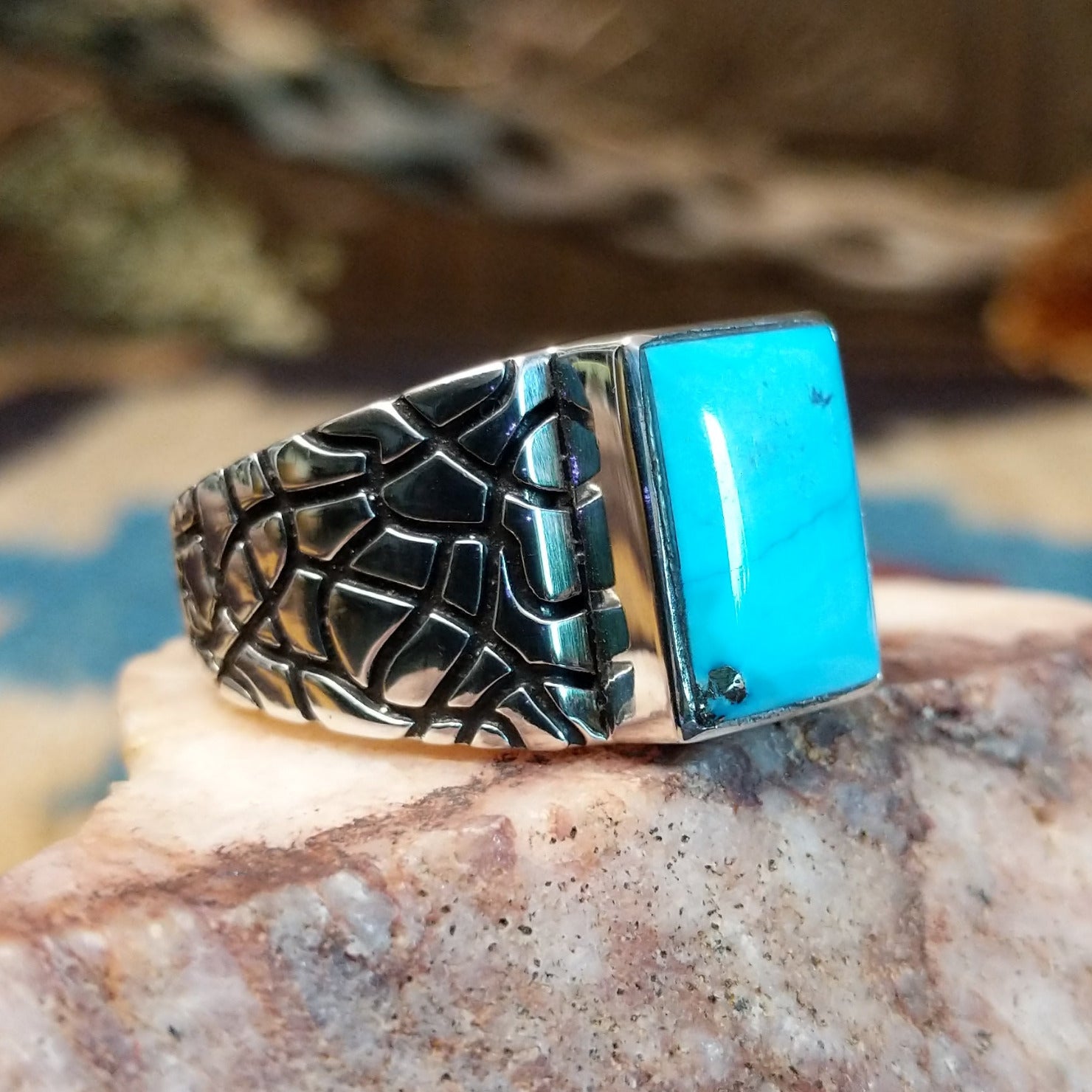 Sterling silver ring with turquoise set in the rectangular bezel and abstract stamped band.