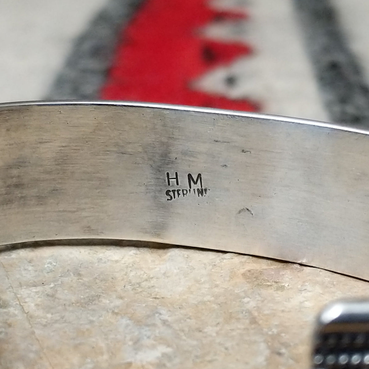 Silver cuff by H.M. featuring an oval blue turquoise stone with brown matrix, centered over an intricate braided silver band with twisted-wire detailing and oxidized accents; artisan and Sterling Silver stamp.