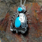Handcrafted sterling silver bug pin with two turquoise stones and hand-stamped Navajo details; side view.