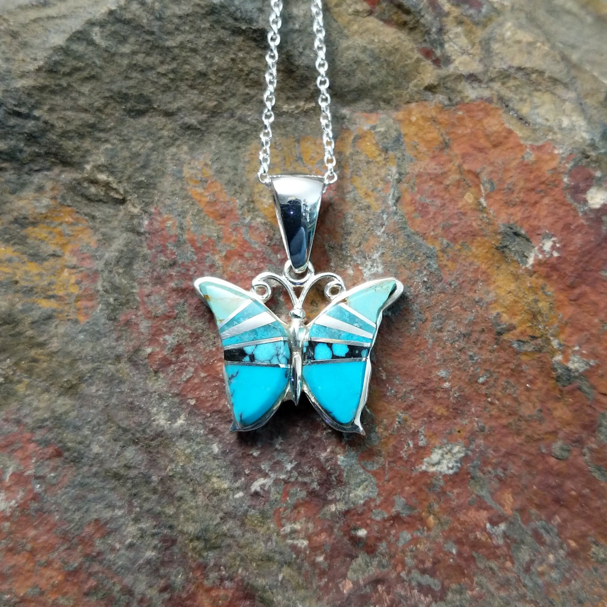 Handcrafted sterling silver turquoise butterfly pendant by Valerie Yazzie, featuring different shades of turquoise inlay in a butterfly design.