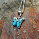 Handcrafted sterling silver turquoise butterfly pendant by Valerie Yazzie, featuring different shades of turquoise inlay in a butterfly design; side view.