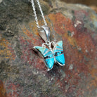 Handcrafted sterling silver turquoise butterfly pendant by Valerie Yazzie, featuring different shades of turquoise inlay in a butterfly design; side view.