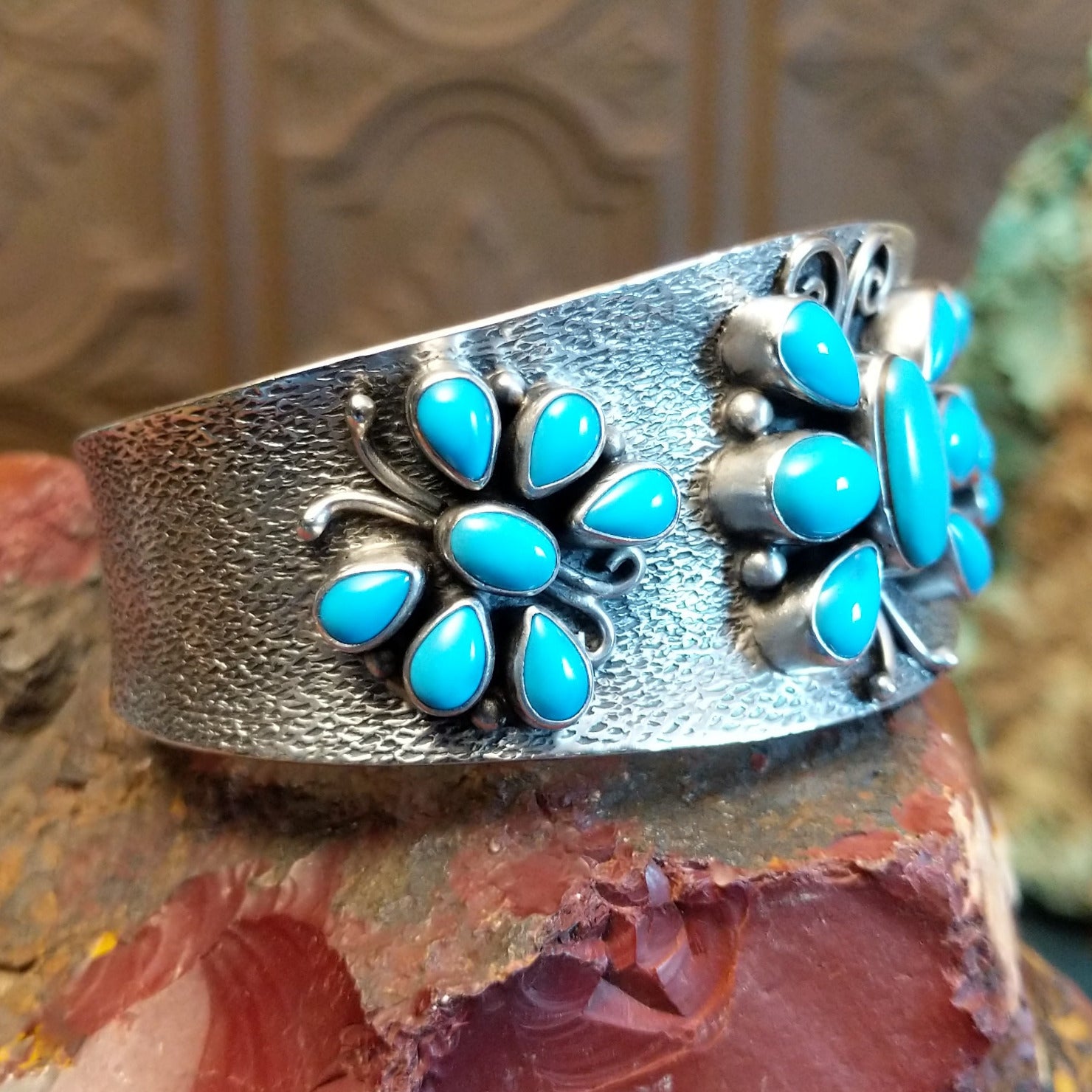 Sterling silver cuff bracelet features turquoise set in bezels creating butterfly motifs along the hammered surface.