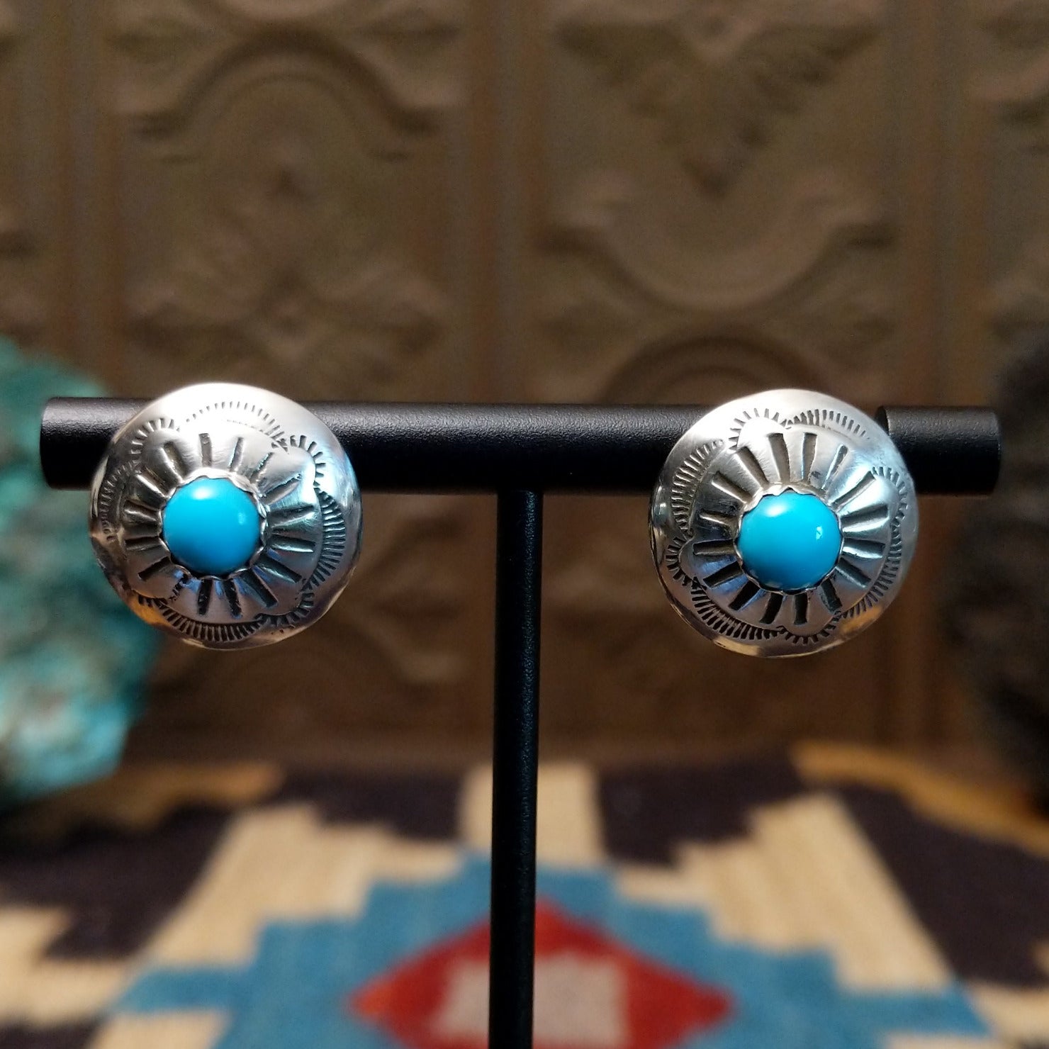 Sterling silver earrings with turquoise set in round bezels, framed by stamped setting. 