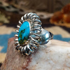 Sterling silver ring with turquoise set in the large oval bezel, framed by coiled silverwork.