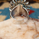 Sterling silver ring with turquoise set in the large oval bezel, framed by coiled silverwork.