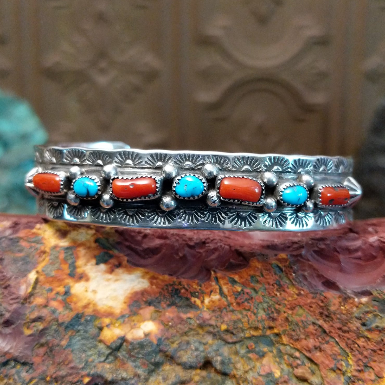 Sterling silver cuff featuring turquoise and coral set in notched bezels.