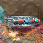 Sterling silver cuff featuring turquoise and coral set in notched bezels.
