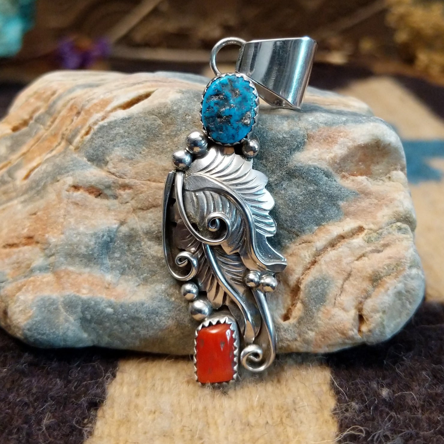 Sterling silver pendant with turquoise and coral set in notched bezels and feather silverwork.