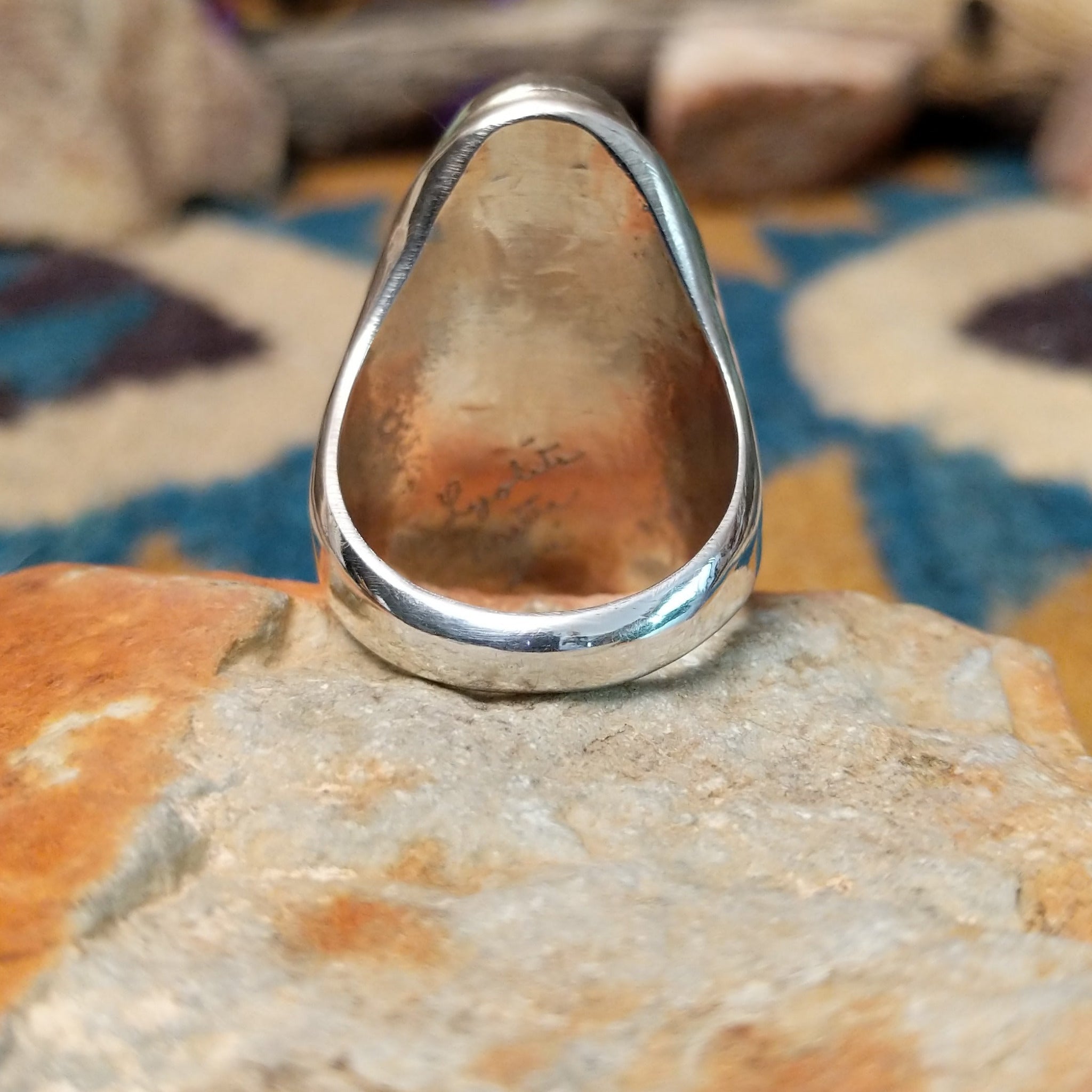 Sterling silver turquoise and coral ring by Lyolita Tsatte featuring a carved blue turquoise stone and ribbed red coral accent; underside view.