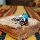 Turquoise & Coral Snake Ring by Effie Calavaza featuring turquoise and coral stones, a decorative silver snake motif with turquoise accents, sawtooth bezels, and a polished silver band; side view.