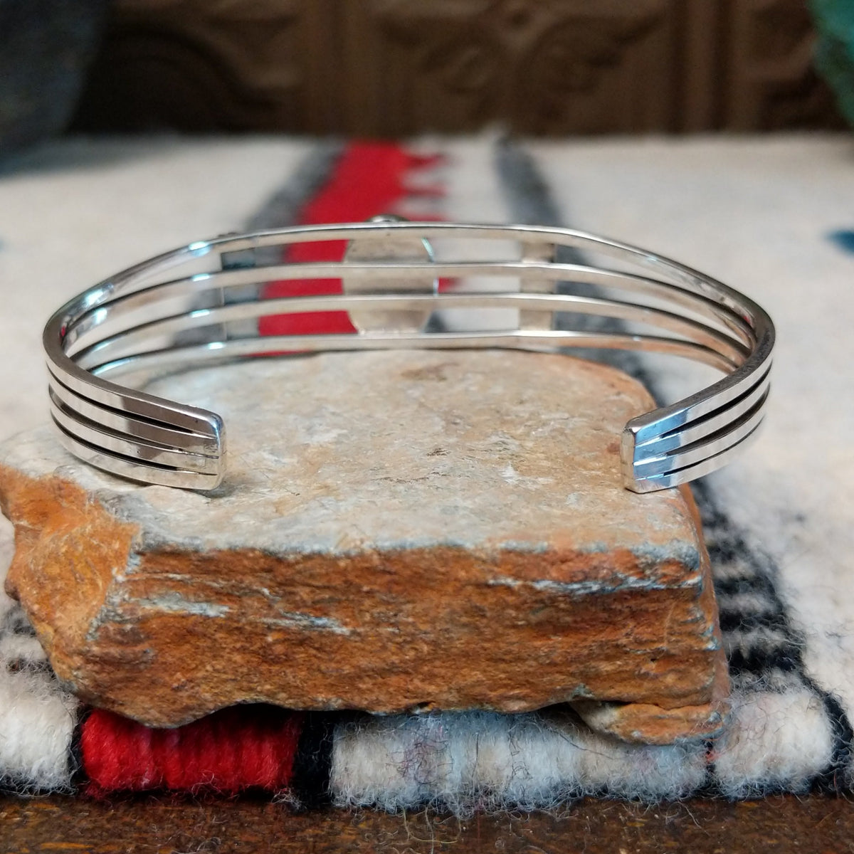 Silver cuff by Thomas Yazzie featuring a smooth oval blue turquoise stone centered within five slender silver bands and flanked by vertical beaded silver accents; underside view.
