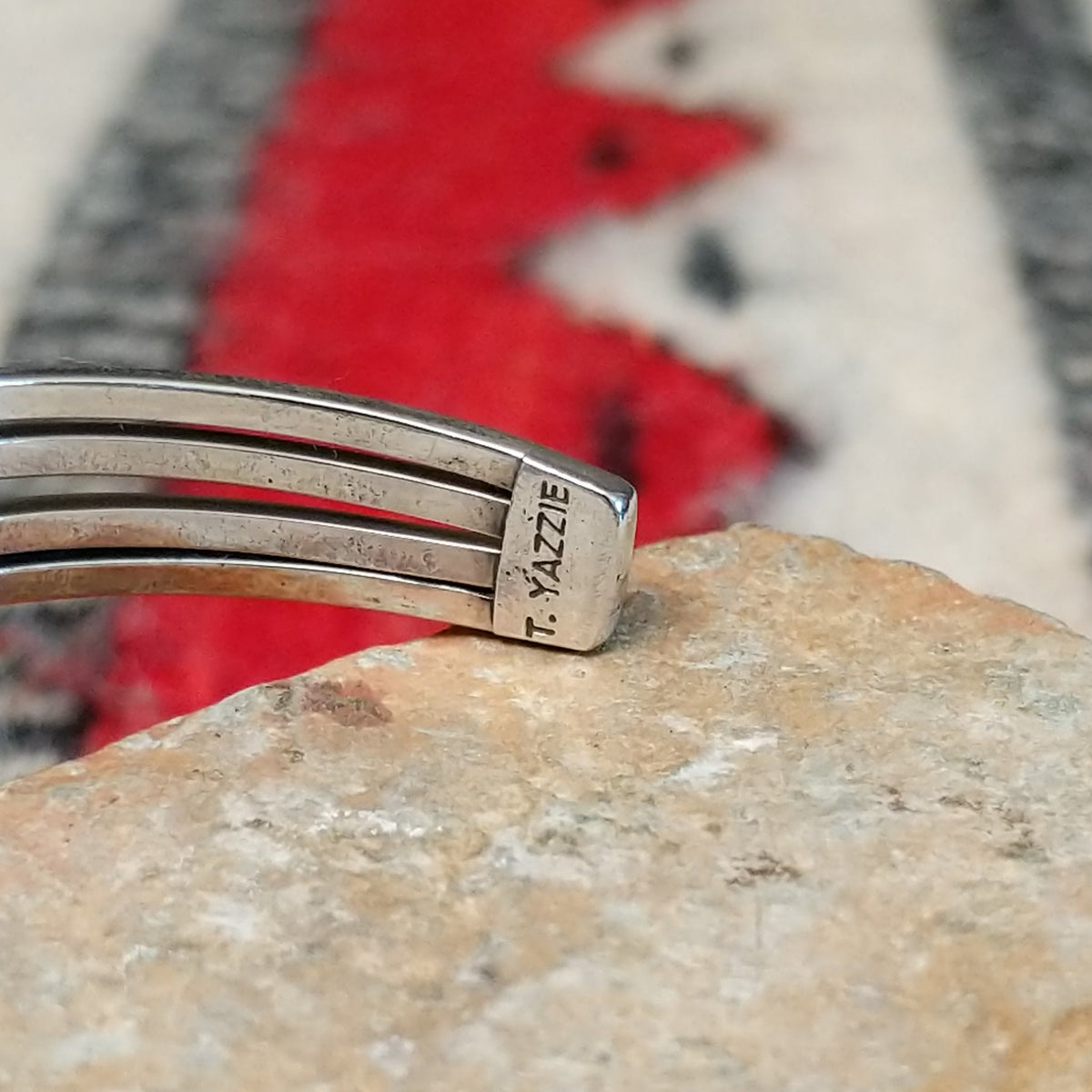 Silver cuff by Thomas Yazzie featuring a smooth oval blue turquoise stone centered within five slender silver bands and flanked by vertical beaded silver accents; artisan stamp.