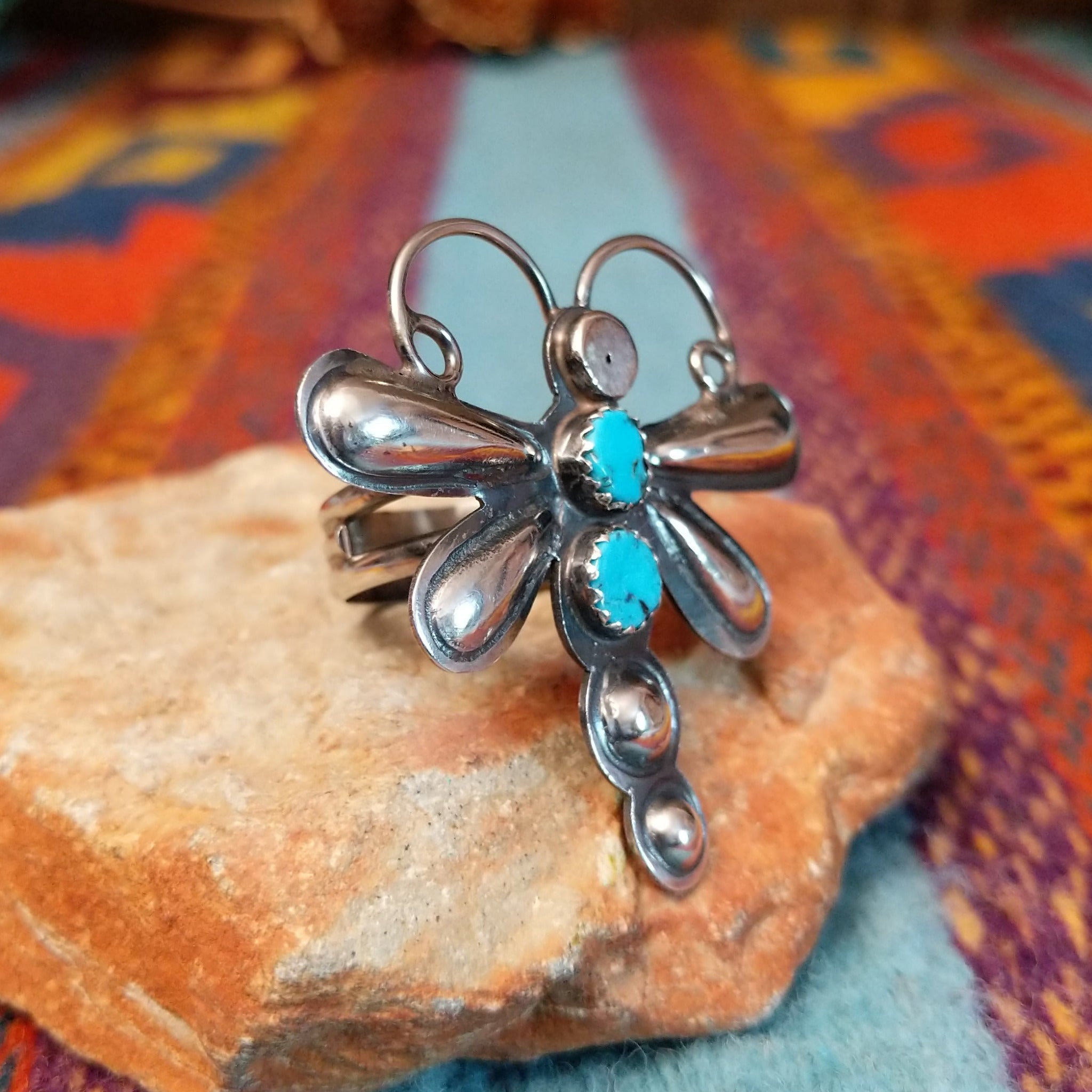 Turquoise Dragonfly Ring by Tim Yazzie featuring two turquoise stones set in Sterling Silver with polished wings, curled antennae, and dimensional silver accents; side view.