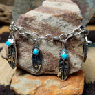 Turquoise feather charm bracelet by Elgin Tom with sterling silver feathers and natural turquoise accents.