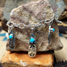 Turquoise feather charm bracelet by Elgin Tom with sterling silver feathers and natural turquoise accents.