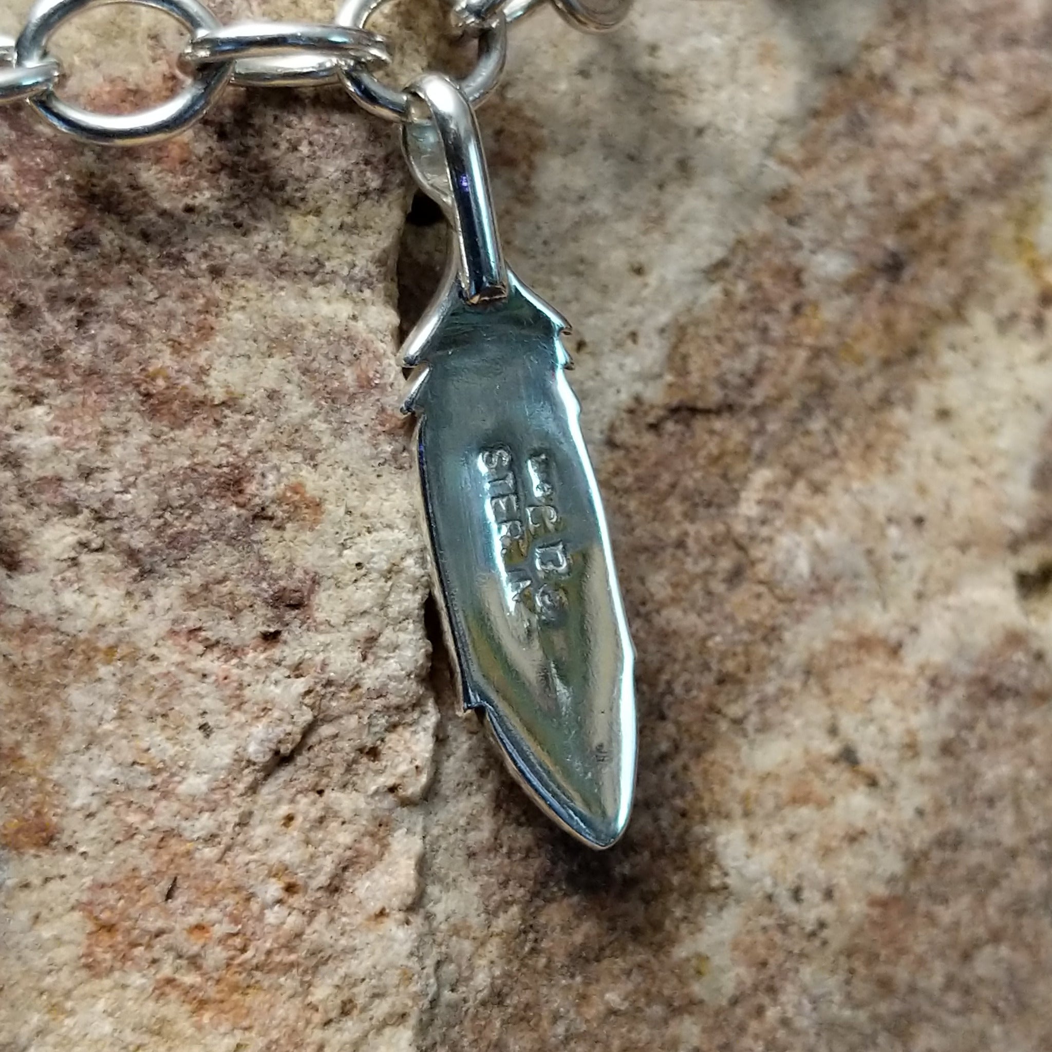 Turquoise feather charm bracelet by Elgin Tom with sterling silver feathers and natural turquoise accents; artisan and Sterling Silver stamp.