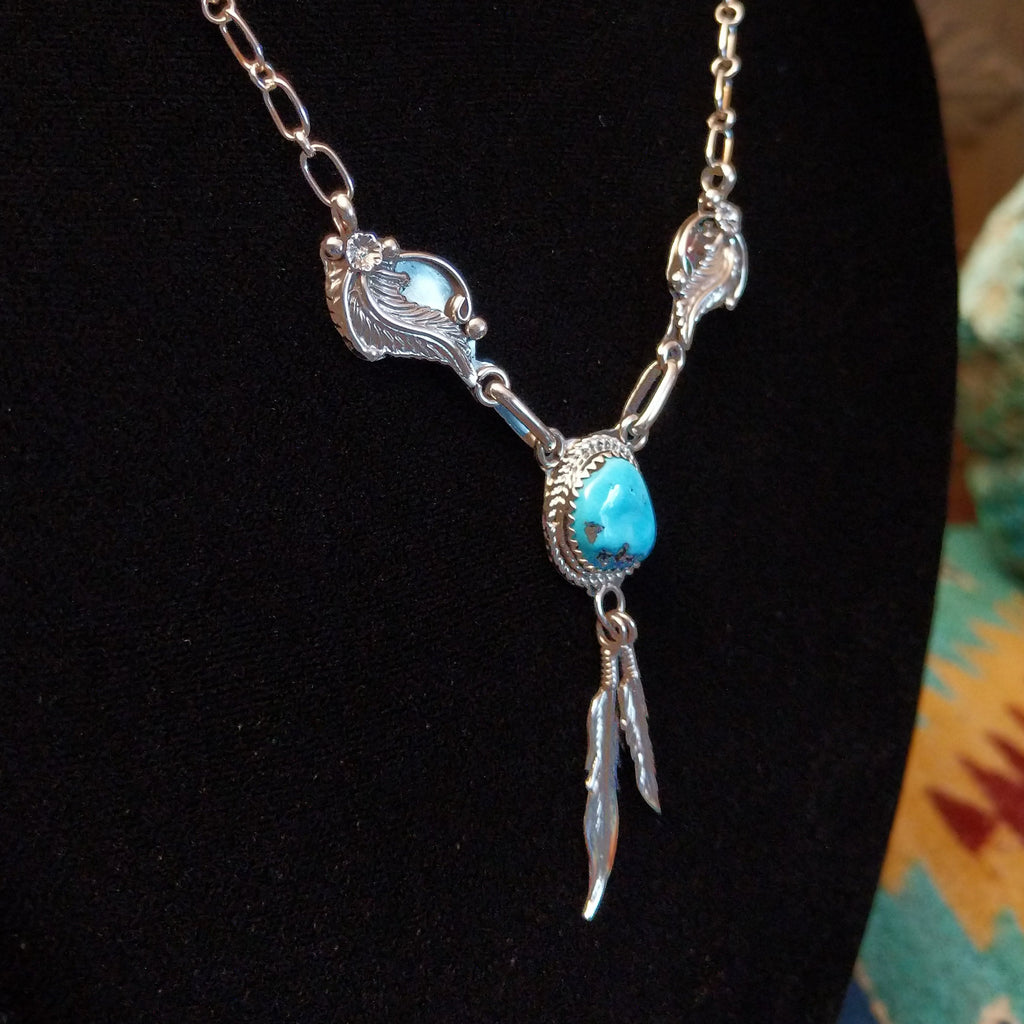 Sterling silver necklace with turquoise centerpiece and feather motifs.