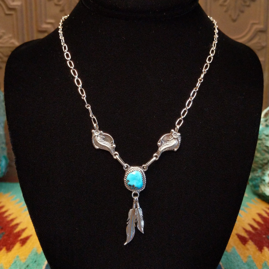 Sterling silver necklace with turquoise centerpiece and feather motifs.