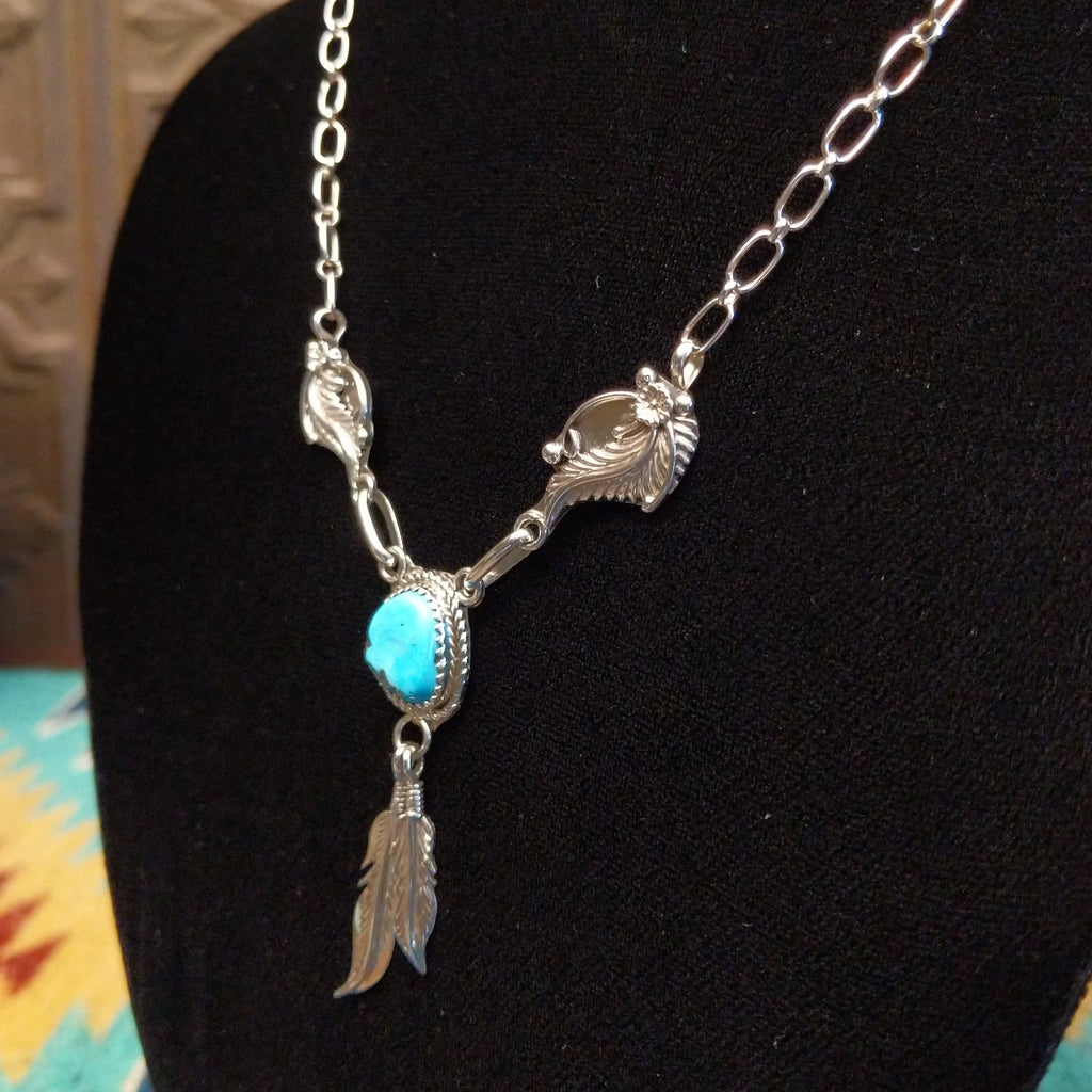 Sterling silver necklace with turquoise centerpiece and feather motifs.