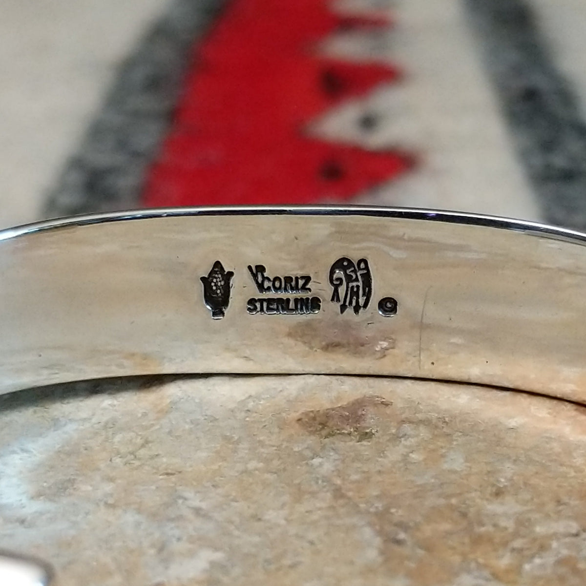 Silver cuff by Raymond Coriz featuring vibrant turquoise inlay with natural matrix and intricate geometric silver channel designs; artisan and Sterling Silver stamp.