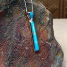 Turquoise inlay pendant by Stacy Spencer featuring an elongated geometric design with vibrant turquoise sections set in polished sterling silver and a turquoise-inlaid bail; side view.