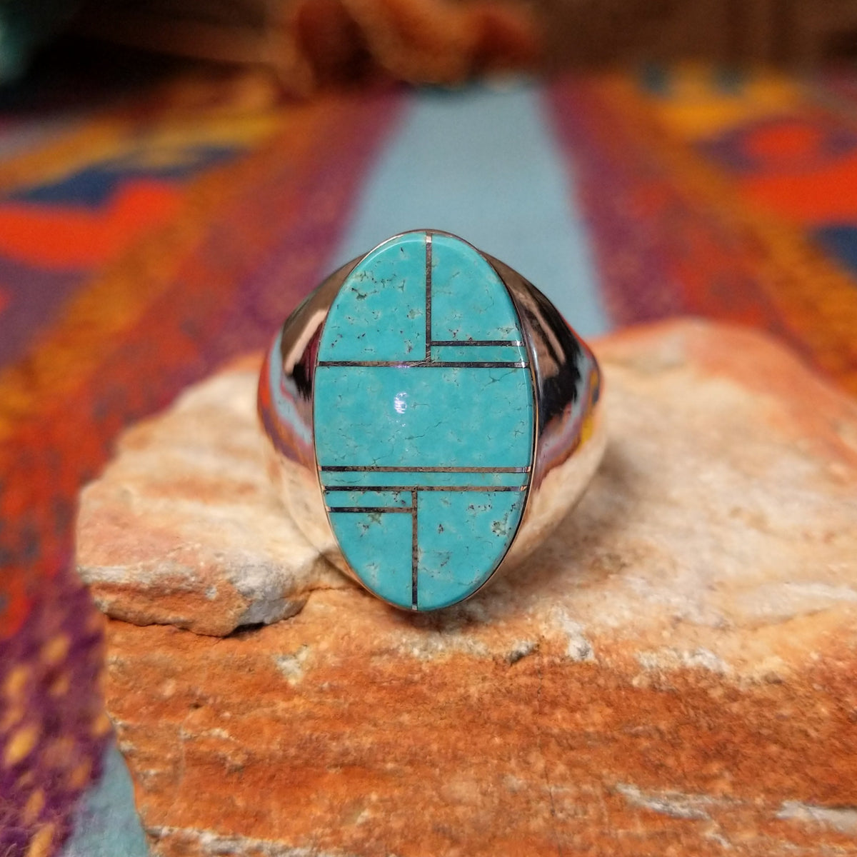 Turquoise Inlay Ring by Wilbert Grey featuring an elongated oval turquoise face with natural matrix, geometric silver channel inlay, and a polished tapered silver band.