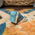 Handcrafted Navajo sterling silver ring by Wilbert Grey featuring a square turquoise mosaic inlay with natural black matrix, set in a polished bezel with a bold geometric design; side view.