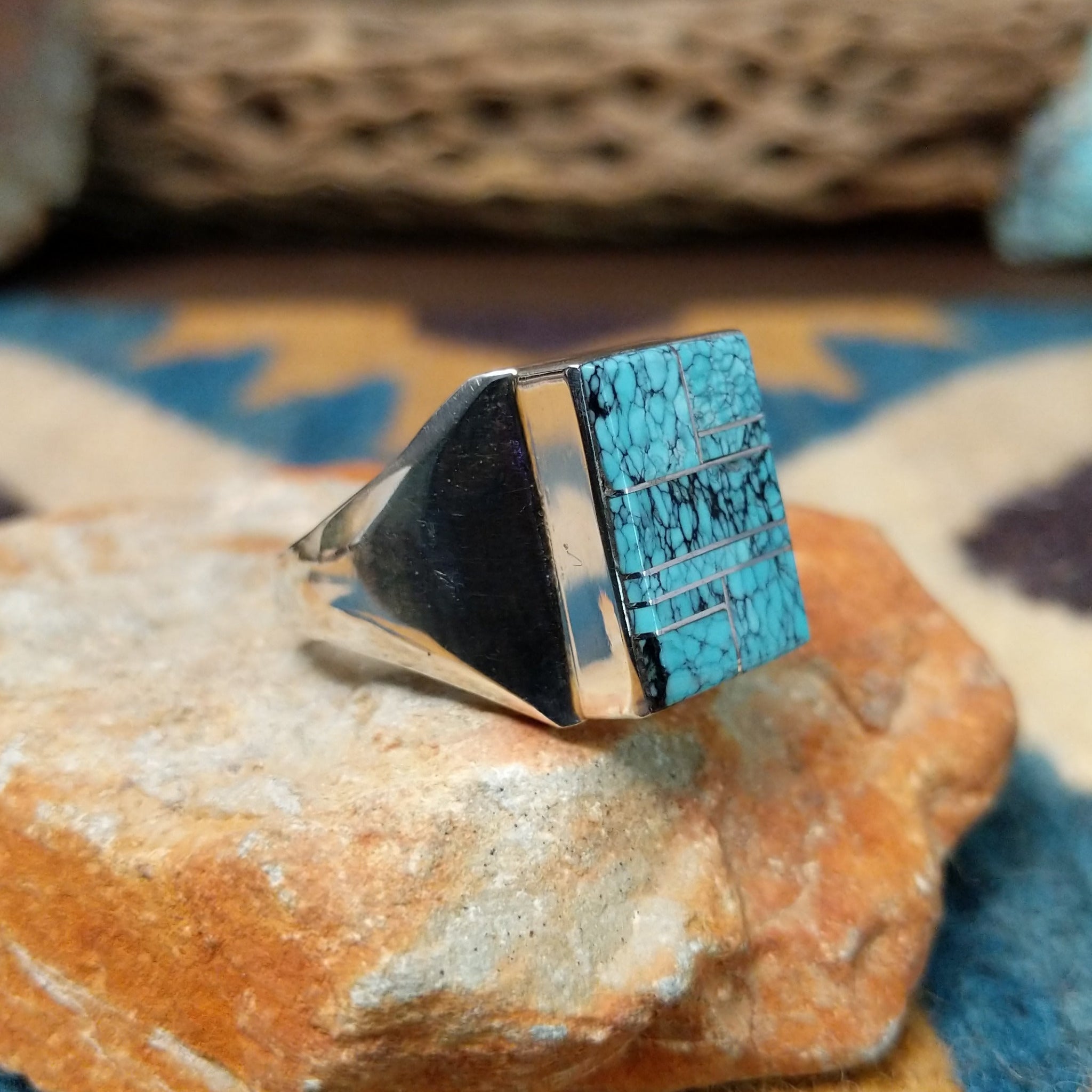 Handcrafted Navajo sterling silver ring by Wilbert Grey featuring a square turquoise mosaic inlay with natural black matrix, set in a polished bezel with a bold geometric design; side view.