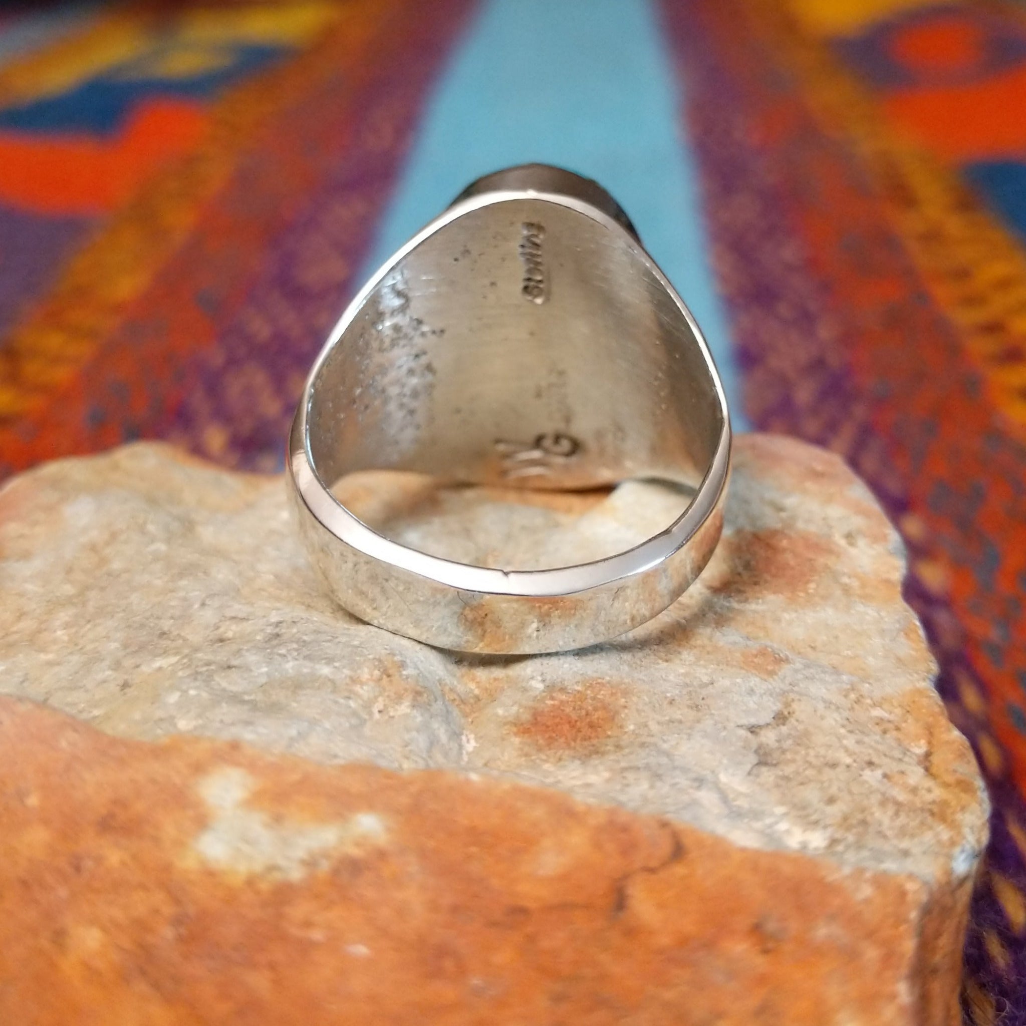 Turquoise Inlay Ring by Wilbert Grey featuring an oval turquoise face with natural brown and green matrix, divided by geometric silver channels and set in a wide polished silver band; underside view.