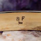 Close up of artist's stamped signature and stamped 14K, indicating 14 karat gold construction.